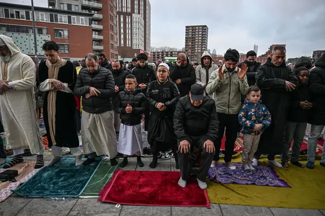 Мужчины и мальчики в носках, на молитвенных ковриках, с руками, сцепленными перед собой для молитвы