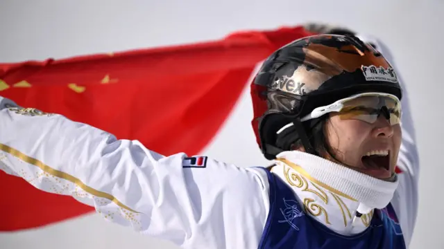 Золотая медалистка Сюй Ментао из Китая празднует победу с национальным флагом после финала женского фристайла