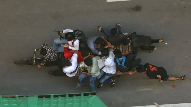 Protesters are carrying the body of a wounded demonstrator along Karwan Bazar Road in Dhaka, Bangladesh, on August 4, 2024,