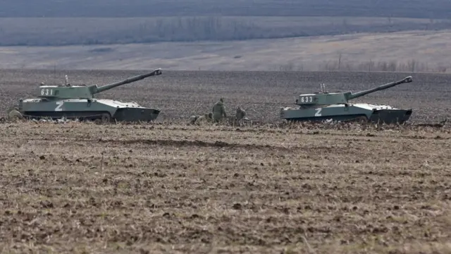 Los miembros del servicio de las tropas prorrusas en uniformes sin insignias se ven junto a vehículos blindados en la región de Donetsk.