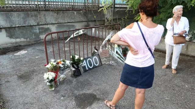 Women look at a display of flowers as they stand at the site where a woman was found dead the day before, in Cagnes-sur-Mer on 2 September 2019, making her the 100th victim of femicide in France this year