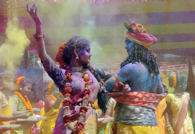 कोलकाता में बसंत उत्सव के मौक़े पर कृष्ण और राधा के रूप में होली खेलते कलाकार.