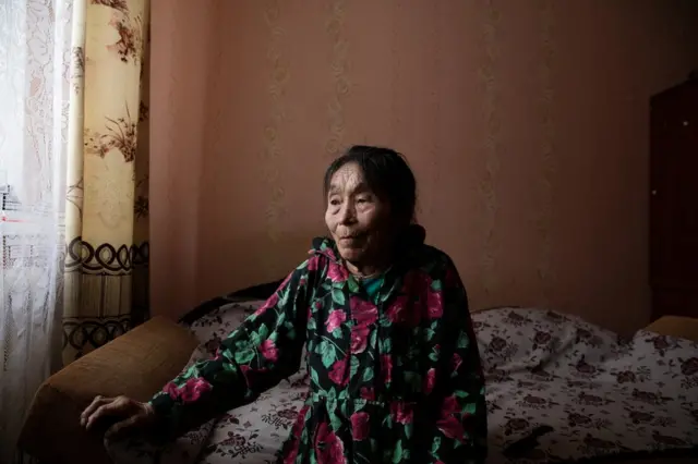 Autipana Audi (born.1941) sitting on her bed in her apartment. Yar-Sale village, Yamal Peninsula, Siberia, Russia.