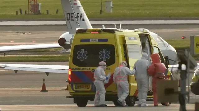 Seseorang mengenakan pakaian hazmat (2R) dan diantar ke ambulans dari pesawat medis yang diduga membawa beberapa penumpang kapal pesiar MV Hondius yang diyakini terinfeksi hantavirus, di bandara Schiphol dekat Amsterdam pada 6 Mei 2026.