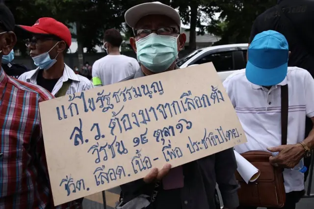 ผู้ชุมนุมคณะประชาชนปลดแอกถือป้ายประท้วง