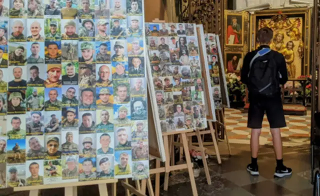 Em học sinh này đã đứng lặng trong nhà thờ trước tượng Đức Mẹ nhiều phút liền. Đằng sau em là ảnh những người lính đã hy sinh.