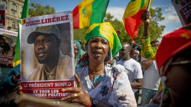 A protester holds up a sign bearing the image of Ousmane Sonko