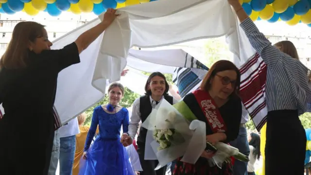 Діти та вчителі, святково одягнені, танцюють під час останнього дзвоника в одній із київських шкіл. 