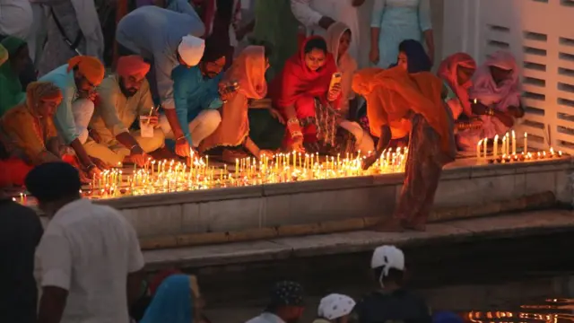 मंदिराच्या तलावाशेजारी भक्तलोक पणत्या लावताना.
