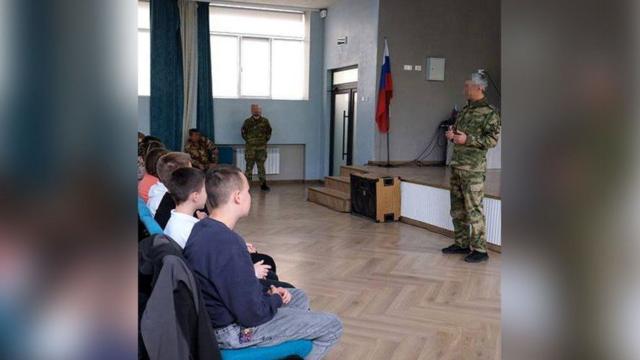 سرباز روسی در مدرسه‌ای در شهر اشغال‌شده ماریو پل با دانش آموزان صحبت می‌کند