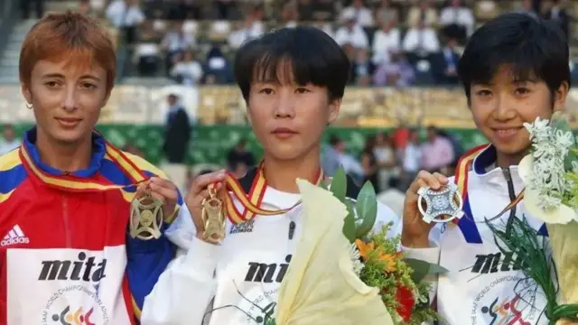 Atlet Korea Utara Jeong Seong-ok (tengah) memenangkan medali emas maraton putri pada Kejuaraan Atletik Dunia 1999 di Seville dan diberi gelar 'pahlawan' di Korea Utara.