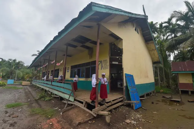 Anak-anak sekolah bermain di bangunan sekolah yang sudah rusak.