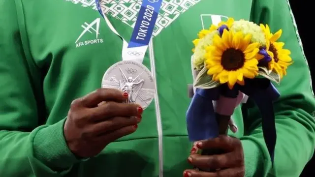 Medalhista segura buquê e medalha