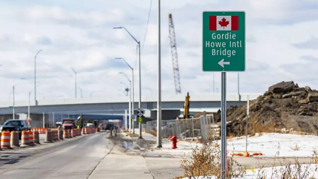 En un lateral de la carretera hay un cartel que indica el Puente Internacional Gordie Howe, con una bandera canadiense y una flecha que apunta a la izquierda. 