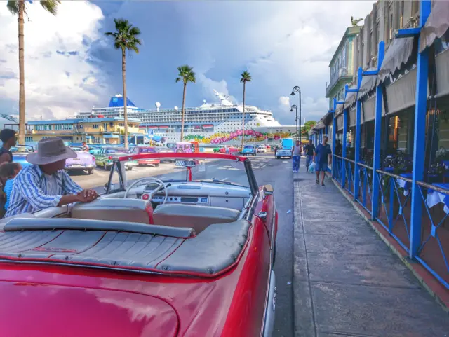 Un auto en La Habana y al fondo, un crucero