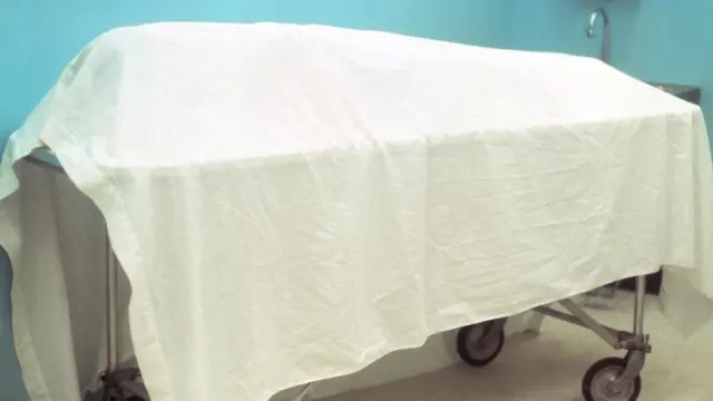 Un cadáver cubierto con una sábana en una camilla