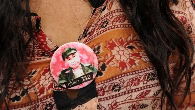 นักเคลื่อนไหวไทยซึ่งติดเข็มกลัดรูปของนายสุรชัย ด่านวัฒนานุสรณ์ ผู้กระทำผิดในคดีหมิ่นพระบรมเดชานุภาพซึ่งถูกตัดสินจำคุก 15 ปี เรียกร้องให้มีการยกเลิกกฎหมายนี้ระหว่างการชุมนุมด้านนอกเรือนจำเมื่อวันที่ 8 พ.ค. 2555