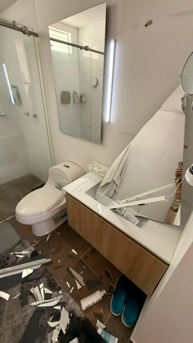 El baño del apartamento de Molina con un espejo roto y varias cosas y restos en en el piso
