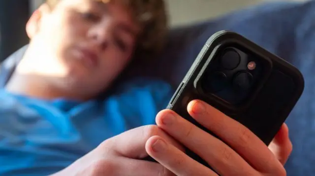 Seorang anak laki-laki berusia 14 tahun melihat layar iPhone.