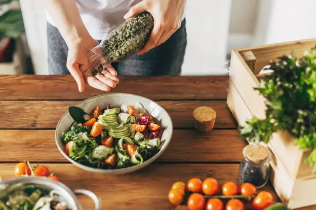 Salata kaseine kabak çekirdeği ekleyen bir el. 