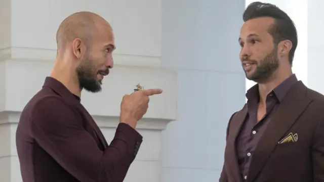 Эндрю Тейт одобрительно указывает пальцем на Тристана Тейта в ходе разговора.