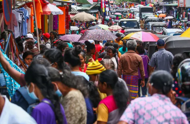 People are gather buy clothes for the upcoming Sinhala Hindu New Year on the busy street market of Maharagama, near Sri Lanka's capital Colombo, on April 7, 2023