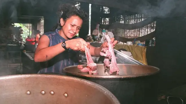 Foto de una mujer en San Salvador cocina iguanas