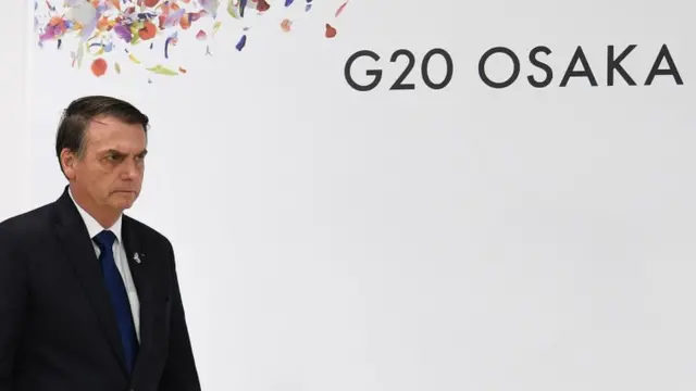 O presidente Jair Bolsonaro próximo a painelfutebol italianoque se lê "G20 Osaka"