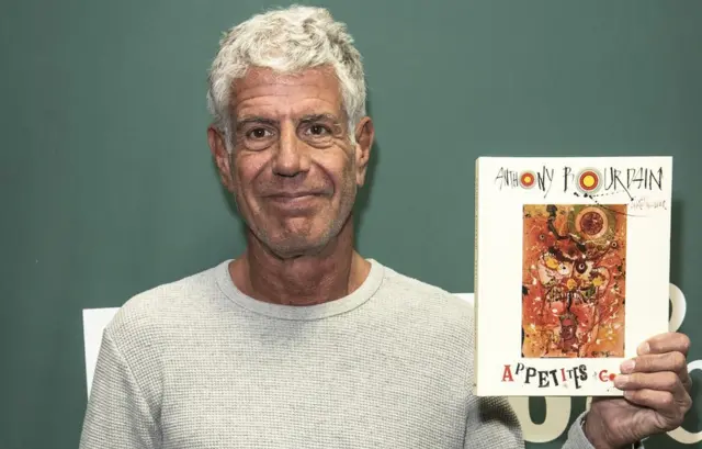 Anthony Bourdain mostrando uno de sus libros.