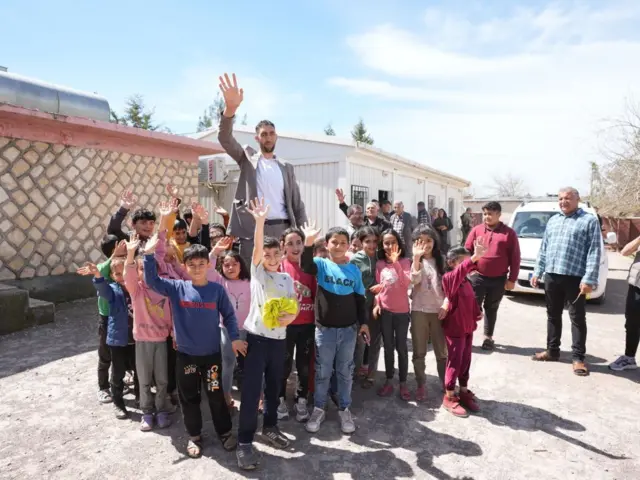 2 metre 51 santimetre boyundaki Sultan Kösen arkada, önünde ve çevresinde çocuklar var, kameraya el sallıyorlar. 