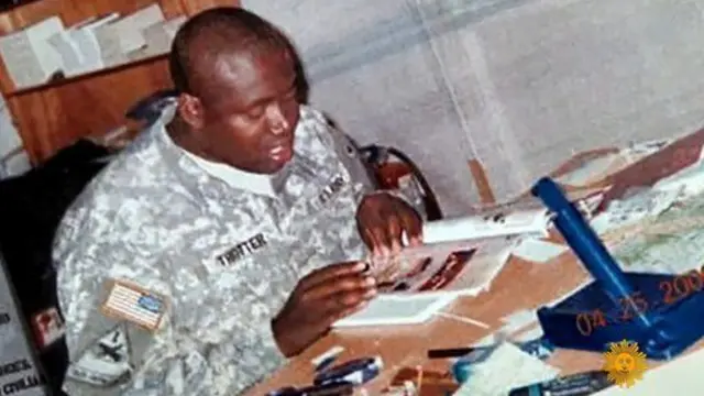 Michael Trotter en tenue militaire qui lit assis à une table