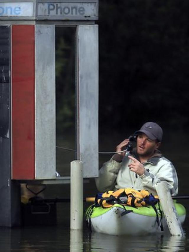 Un hombre habla por teléfono desde una cabina telefónica montado en un bote.