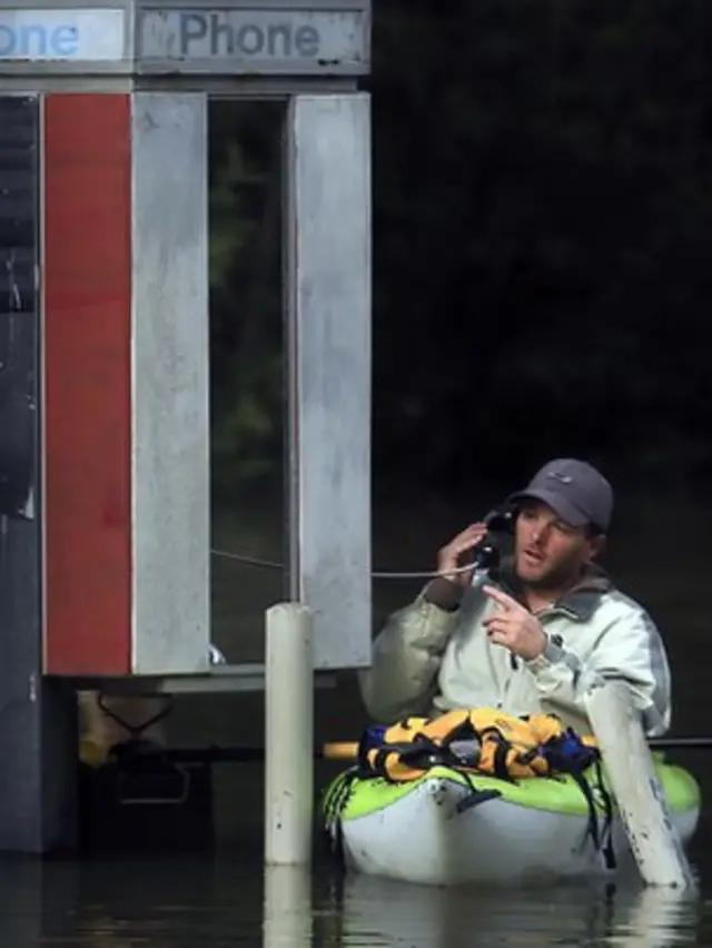 Un hombre habla por teléfono desde una cabina telefónica montado en un bote.