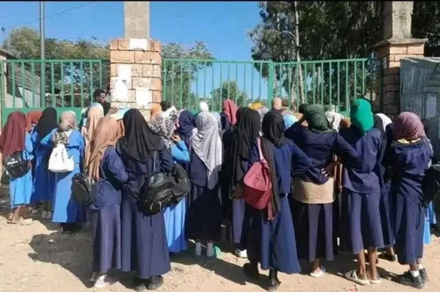 ሕጃብ ዝተኸድና ብዙሓት ተመሃሮ፡ ናብ ዝተዓጽወ ማዕጾ ገጸና እናጠመታ ብድሕሪአን ይርኣያ