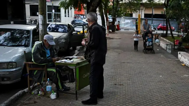 Un hombre cuenta billetes de guaraníes en una calle de Asunción