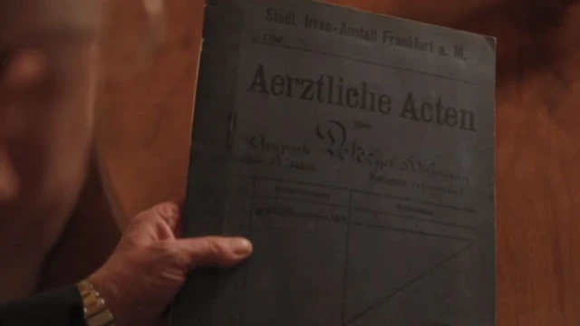 Près d'un siècle plus tard, le psychiatre Maurer a mené une enquête qui a permis de réexaminer le cas d'Auguste. Il montre ici le dossier original du Dr Alzheimer.