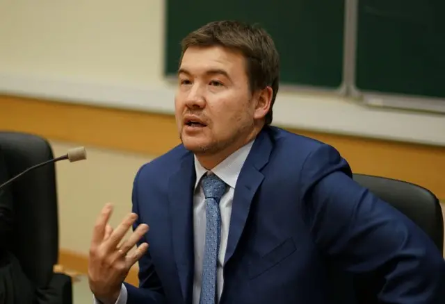 Мужчина в костюме и галстуке перед микрофоном