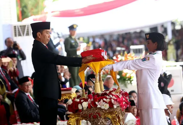 Presiden Joko Widodo (kiri) menyerahkan bendera Indonesia kepada seorang pelajar dalam upacara peringatan HUT ke-71 Kemerdekaan Indonesia di Jakarta pada 17 Agustus 2016.