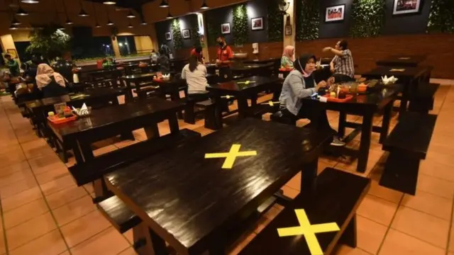 Pengunjung menyantap hidangan di antara meja yang diberi tanda silang di salah satu restoran di Srengseng Sawah, Jakarta Selatan, Kamis (09/04/20).