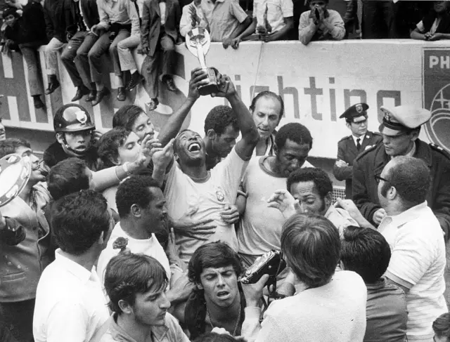 Pelé célèbre la victoire du Brésil en finale contre l'Italie en soulevant le trophée Jues Rimet, entouré de ses coéquipiers - juin 1970.