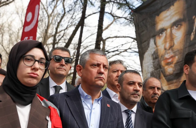 Özgür ÖZel yanında bir başörtülü kadın ve partililerle bir anmada. Arkada Deniz Gezmiş fotoğrafı var.