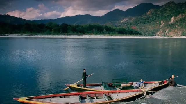 Imagem de um lago e uma pessoa ao lado de dois barcos