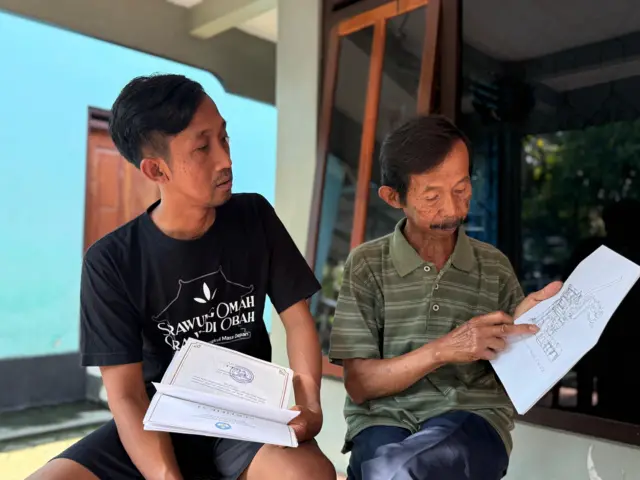 Eka (kiri) bersama ayahnya memegang sketsa batu Candi Borobudur.