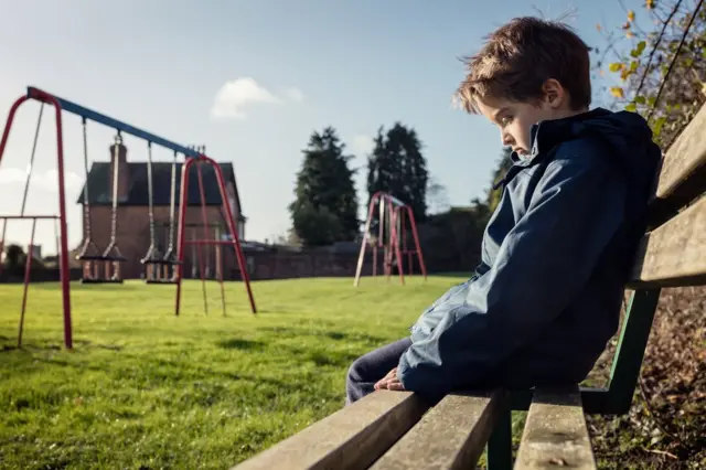 طفل جالس على مقعد في حديقة