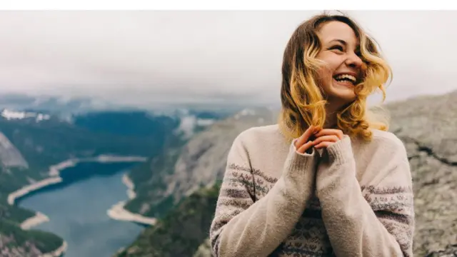 Girl standing on the Trolltunga and laughing