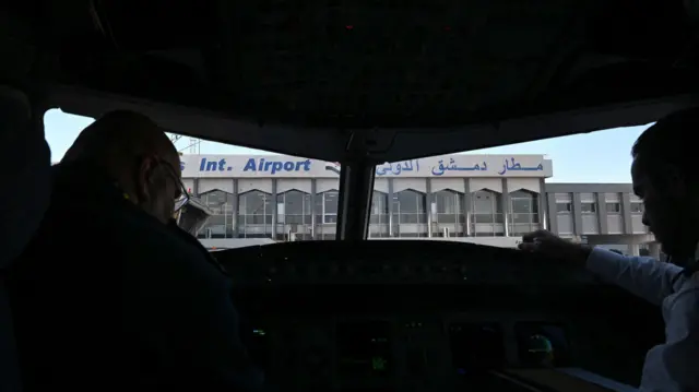 يجلس الطيارون في قمرة القيادة لطائرة تابعة للخطوط الجوية السورية في مطار دمشق الدولي قبل رحلة إلى مدينة حلب، في 18 ديسمبر 2024.