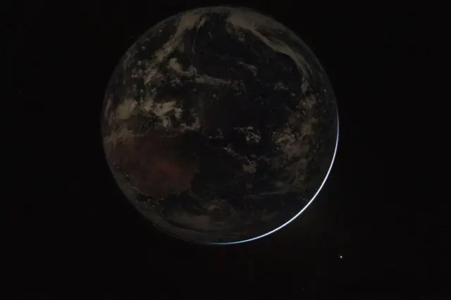 पृथ्वीनं सुर्याला पूर्णपणे झाकून टाकलं असताना, रात्रीच्या वेळेस दिवे चमकत आहेत