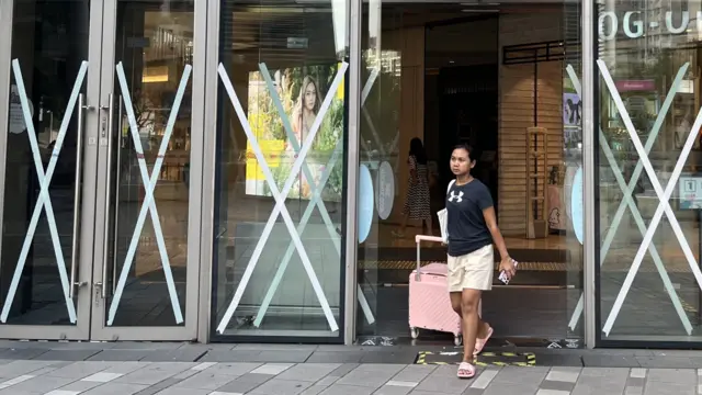 香港将军澳某购物商场一位女士（右）走出贴满皱纹胶卷的玻璃大门（BBC中文图片22/9/2025）
