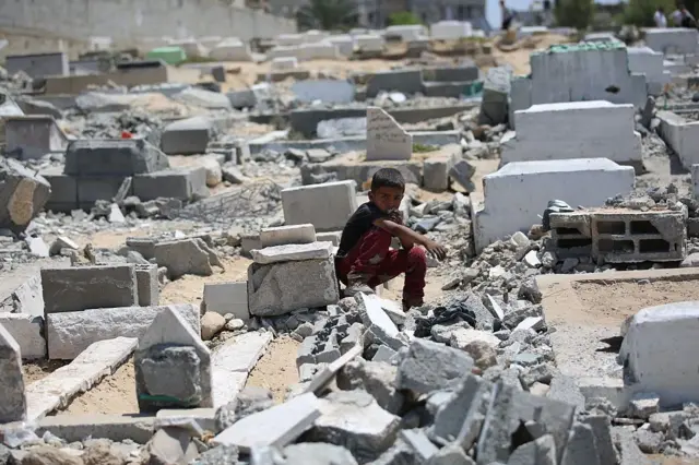طفل يجلس بين الأنقاض في غزة بعد غارة جوية إسرائيلية في يونيو/حزيران
