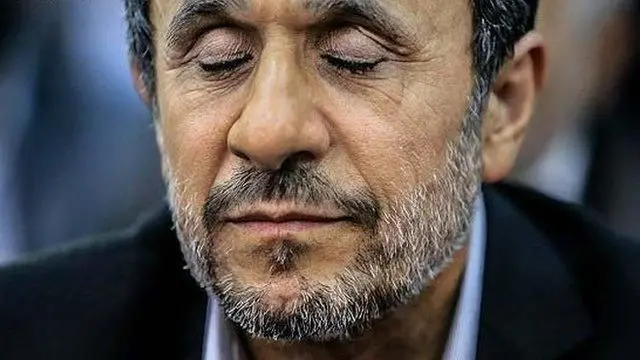 يظهر محمود أحمدي نجاد، مغمض العينين، ويغطي رأسه شعر يمزج بين اللونين الأبيض والأسود، وله لحية خفيفة تمزج أيضاً بين اللونين الأبيض والأسود.